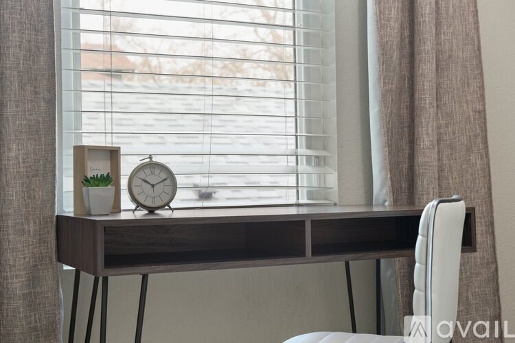 A desk with a clock and a plant on it.