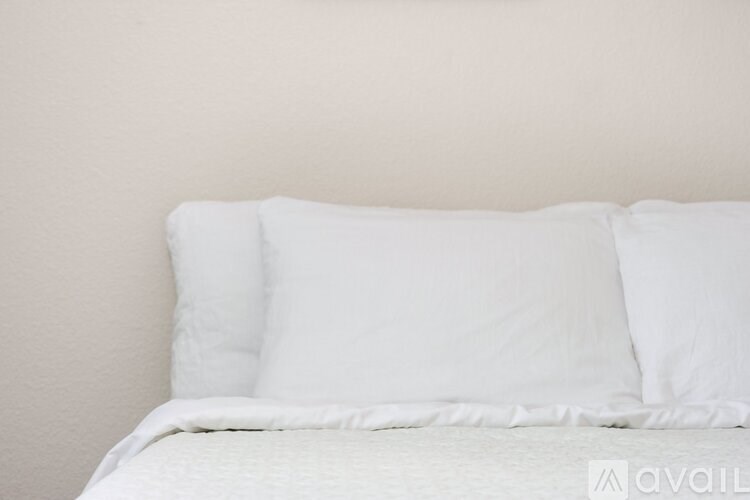 A white bed with two pillows and a white blanket.