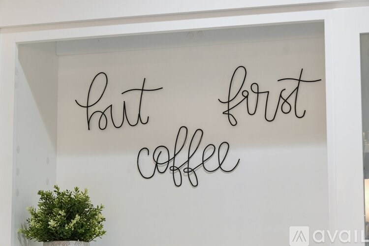 A white wall with the words "but first coffee" written on it.