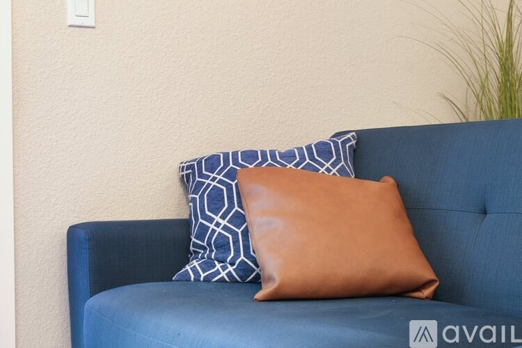 A blue couch with a tan pillow and a blue and white pillow on it.