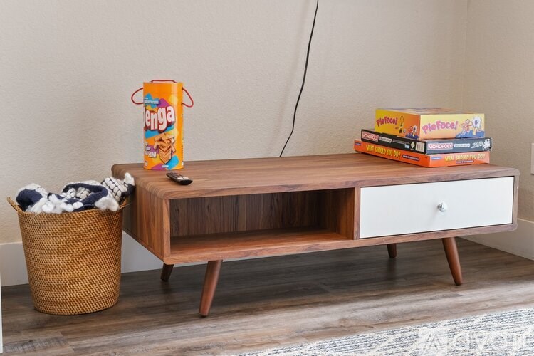 A wooden TV stand with a box of tissues and a basket of laundry on top.