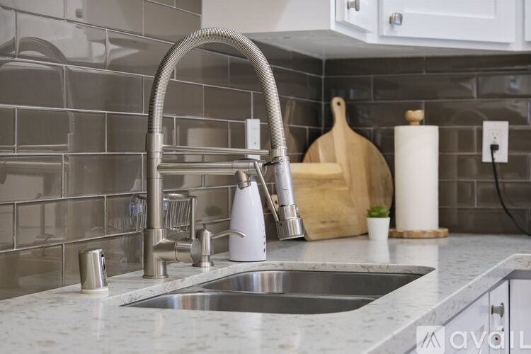 A kitchen sink with a silver faucet and a marble countertop.