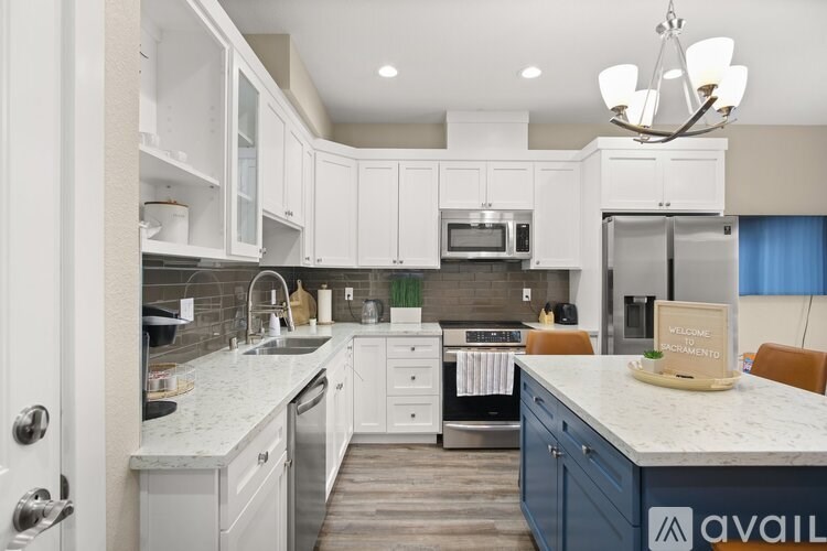 A kitchen with white cabinets and a marble countertop.