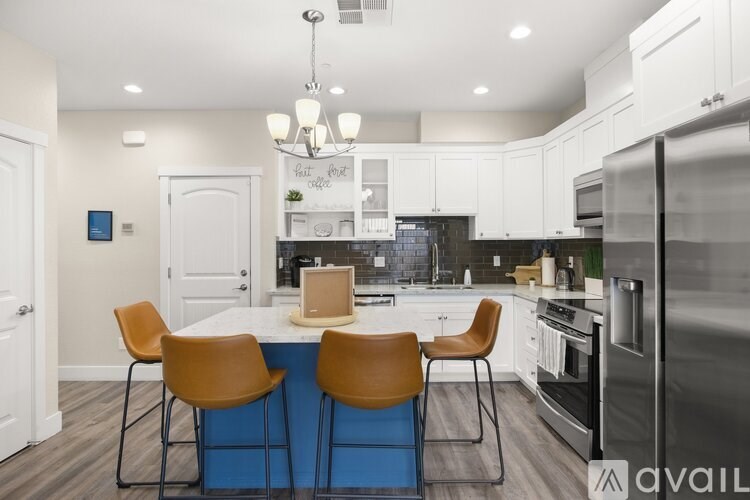 A kitchen with a blue island and brown chairs.