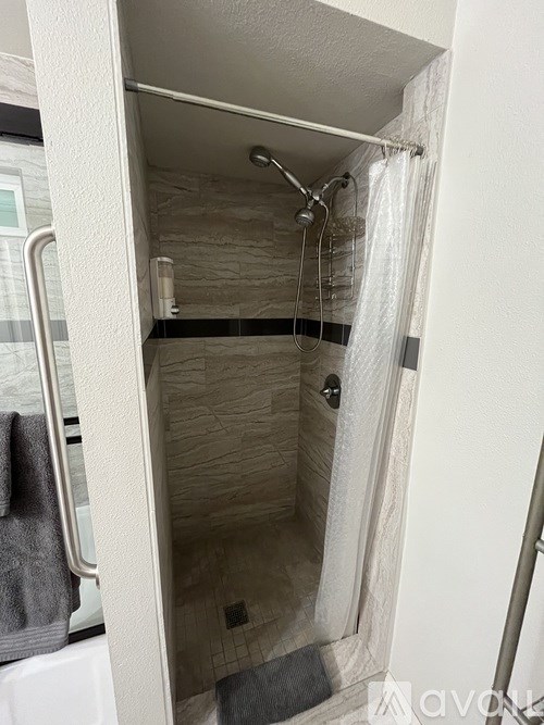 A bathroom with a shower stall and a towel hanging on the door.