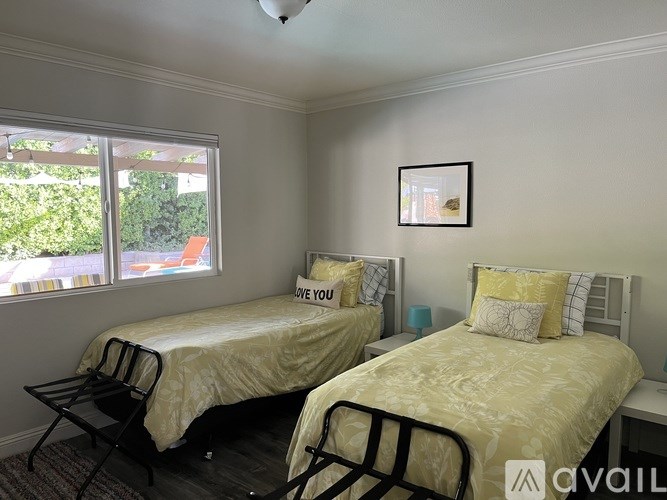 Two twin beds with white bedspreads and pillows in a room with a window.