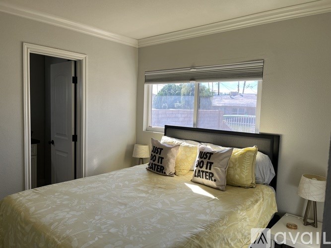 A bedroom with a bed, pillows, and a window with blinds.