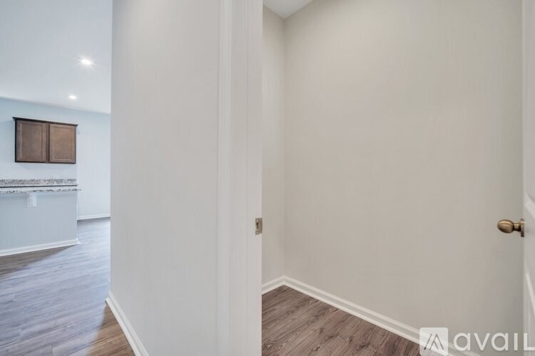 A hallway with a wooden floor and a door on the right.