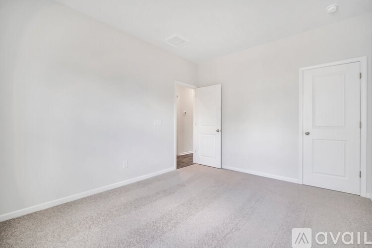 A room with a carpeted floor and two doors.