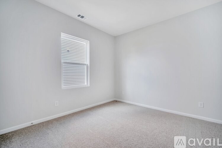 A room with a window and a carpeted floor.