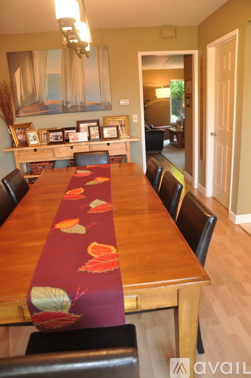 A long wooden table with a red table runner with leaves on it.