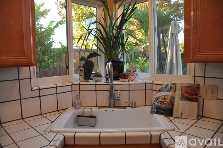 A bathroom with a white tub and a window with a view of trees.