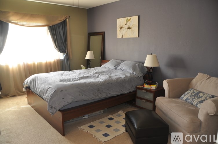 A bedroom with a large bed and a chair.