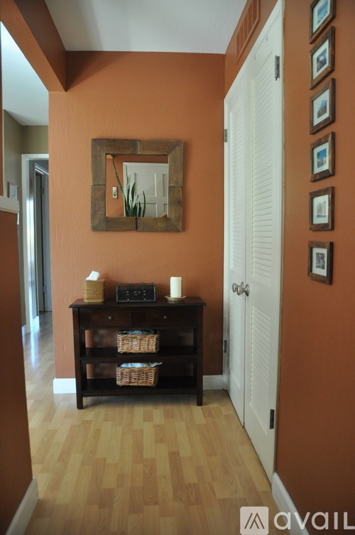 A hallway with a mirror and a shelf with candles and baskets.