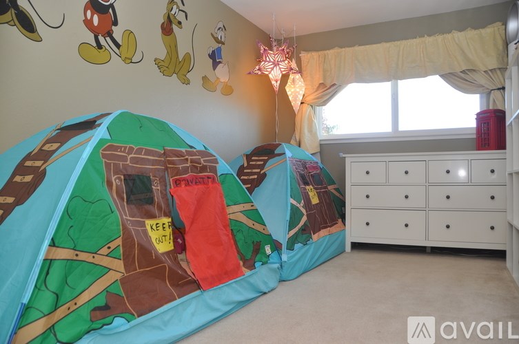 A child's bedroom with a Mickey Mouse wall decal and a bed with a castle print.