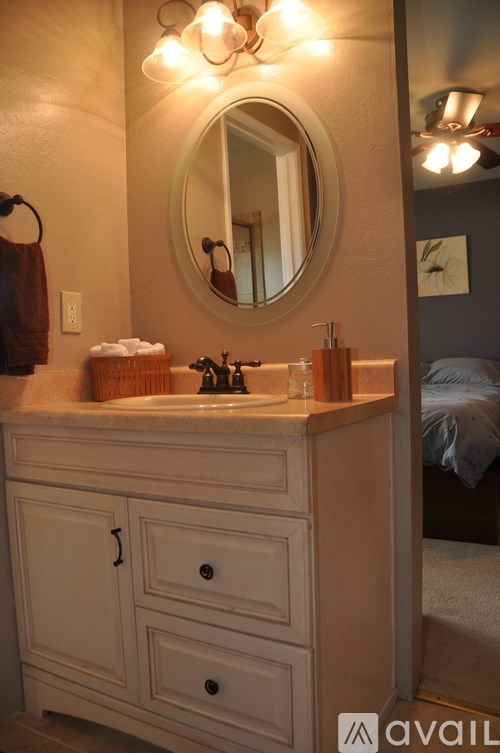 A bathroom with a sink, mirror, and lighting fixture.