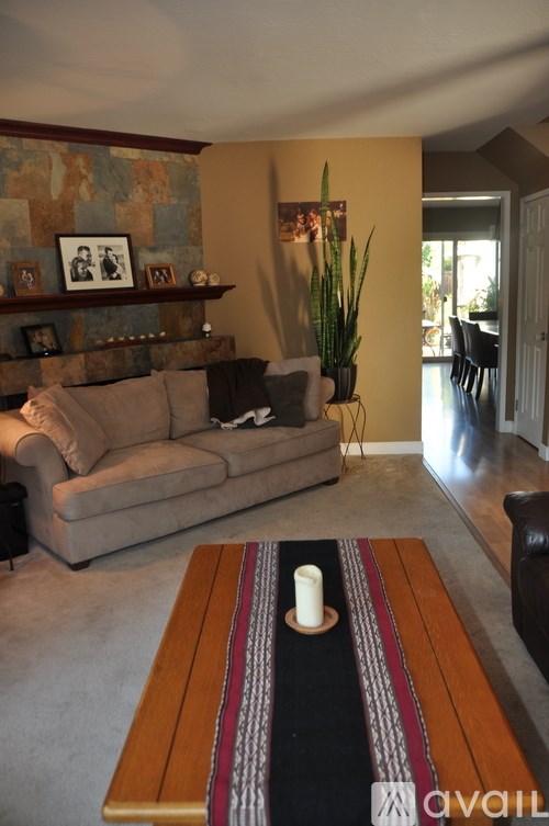 A living room with a couch, a coffee table, and a plant.