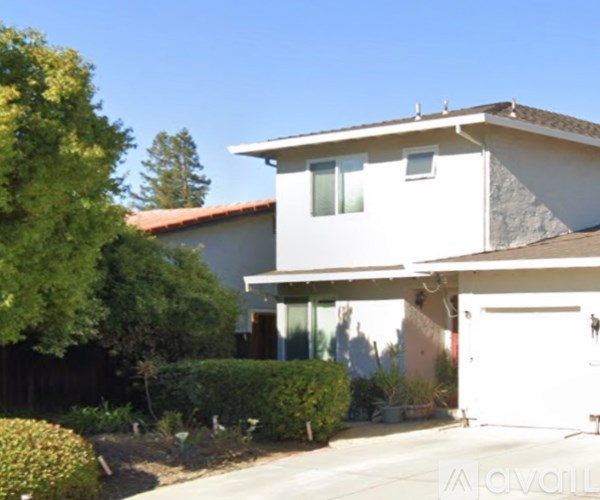 A white house with a brown roof and a garage door.