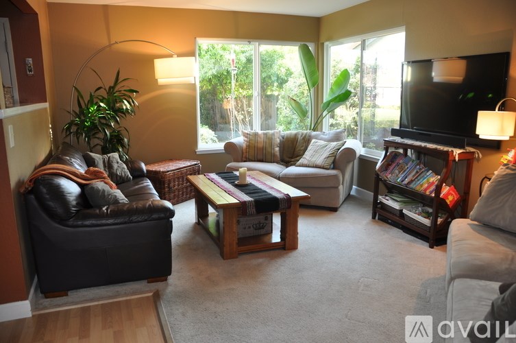 A living room with a black leather couch, a wooden coffee table, and a flat screen TV.