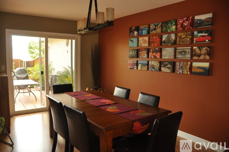 A dining room with a table and chairs and a wall of pictures.