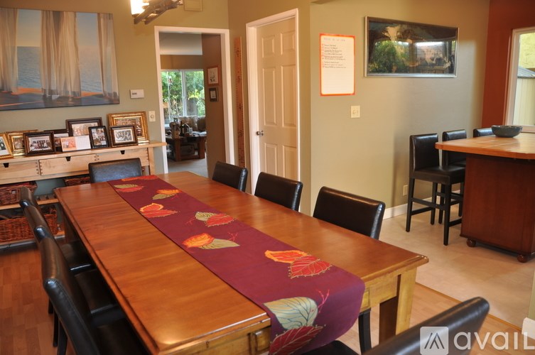A long wooden table with a purple table runner and a row of chairs.
