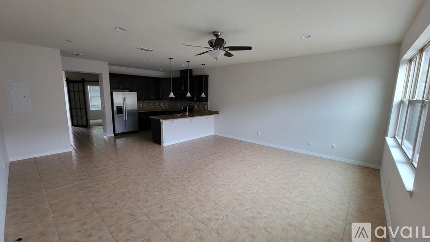 A spacious living room with a kitchen in the background and a tiled floor.