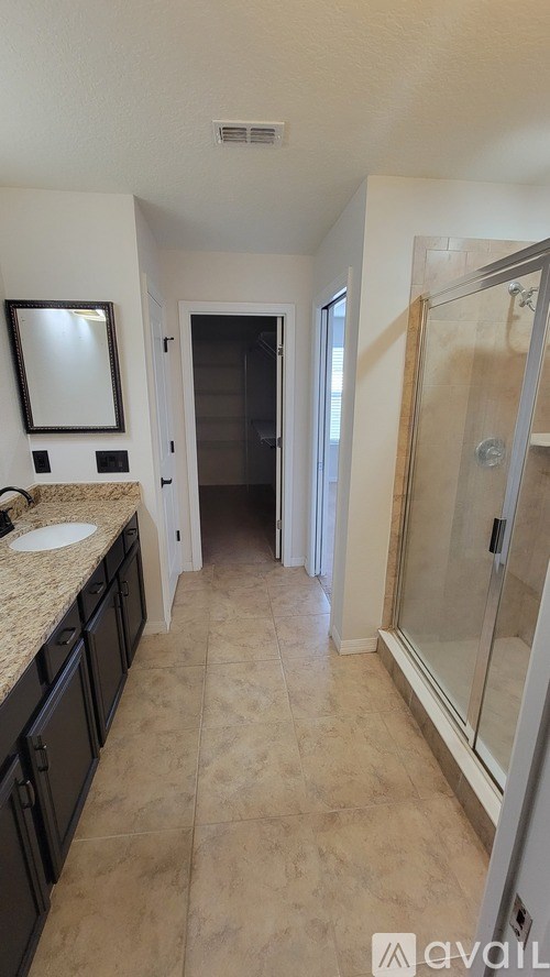 A bathroom with a sink, mirror, and shower.