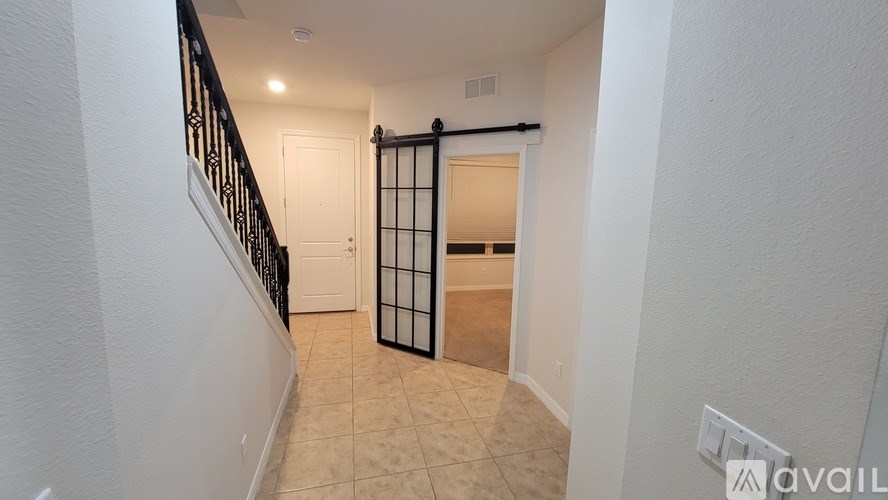 A hallway with a black railing and a white door.