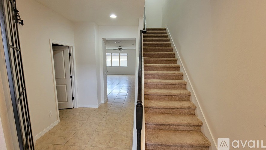 A staircase with a carpeted runner and wooden steps leads up to a small room with a window.