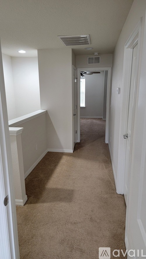 A hallway with carpeted floors and white walls.