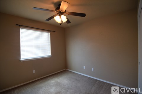 A room with a ceiling fan and a window with blinds.