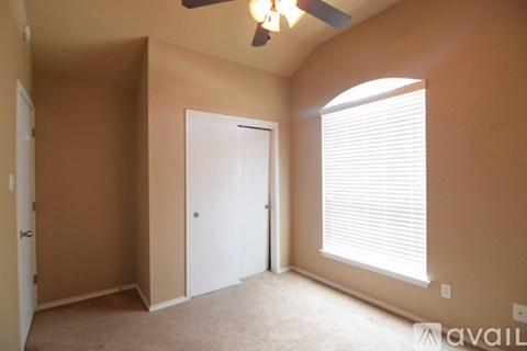 A room with a ceiling fan and a window with blinds.