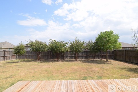 A backyard with a wooden deck and a fence.