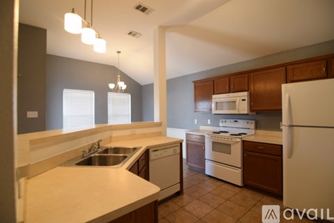 A kitchen with white appliances and brown cabinets.