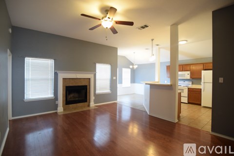 A spacious living room with a fireplace and a ceiling fan.