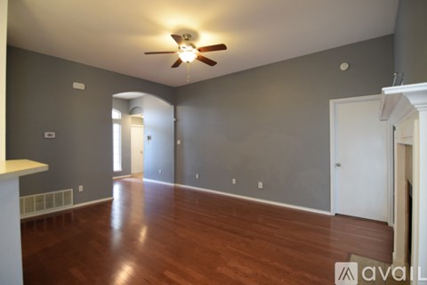 A spacious room with a ceiling fan and wooden flooring.