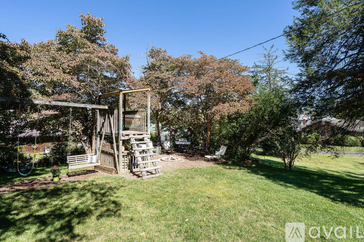 A wooden swing set is situated in a grassy backyard.