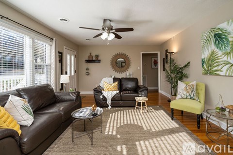 A living room with a black leather couch and a green armchair.