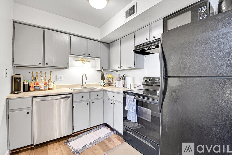A kitchen with a black fridge and white cabinets.