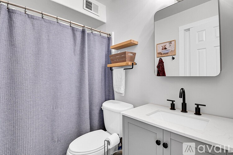 A bathroom with a white toilet, a white sink, and a purple shower curtain.