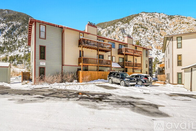 A row of multi-story buildings with cars parked in front.