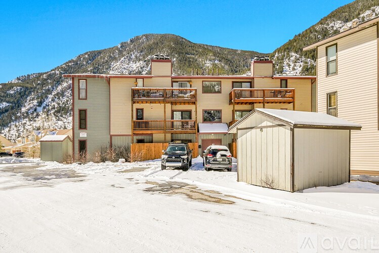 A large building with a balcony is in the foreground with a mountain in the background.