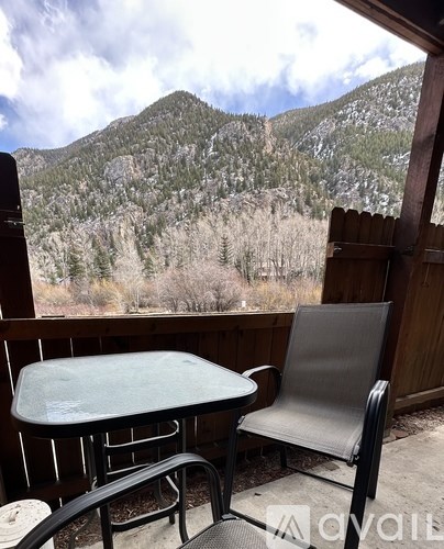 A table and chair set on a balcony overlooking a mountain.