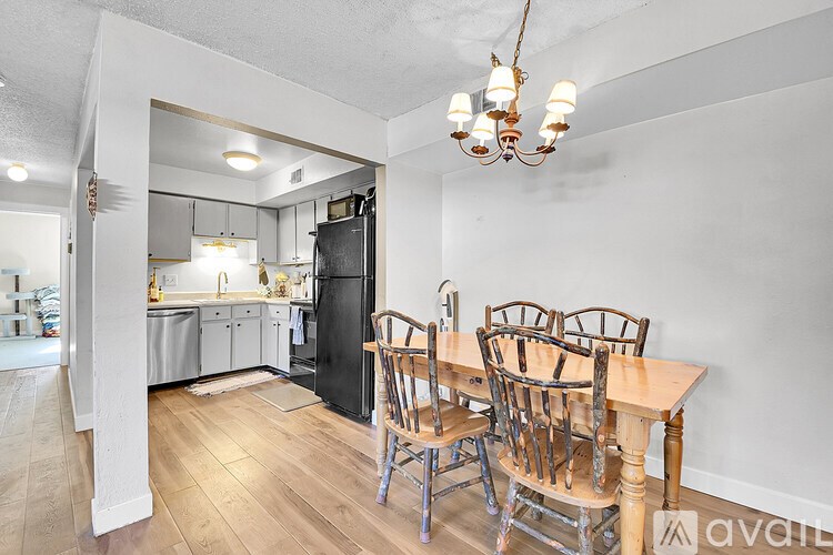 A kitchen with a table and chairs in the foreground and a kitchen in the background.