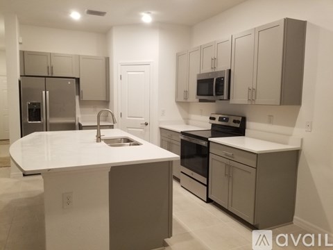 A kitchen with a white counter top and stainless steel appliances.
