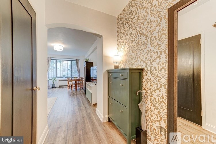 A hallway with a green cabinet and a wooden floor.