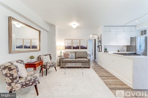 A living room with a couch, chair, and a painting on the wall.