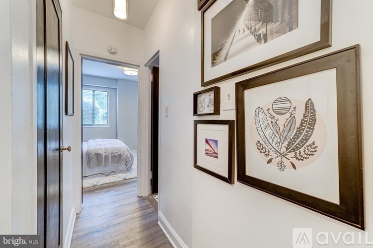 A hallway with a bedroom at the end and pictures on the wall.