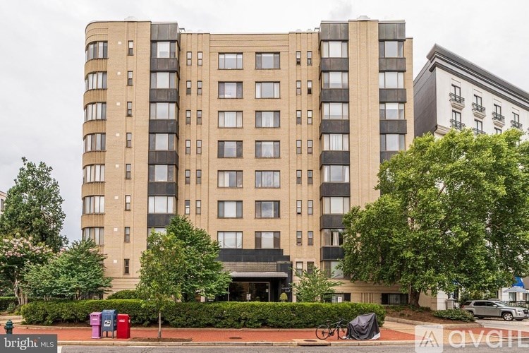 A tall apartment building with a parking lot in front.