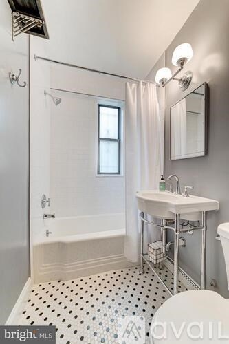 A white sink with a silver faucet is on a stand in a bathroom.